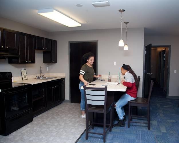 two students talking in the kitchen, featuring a breakfast bar